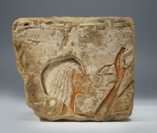 Sandsteinblock mit Relief der Königin Nofretete im Profil. Sie hebt die hand wie zum Gruß