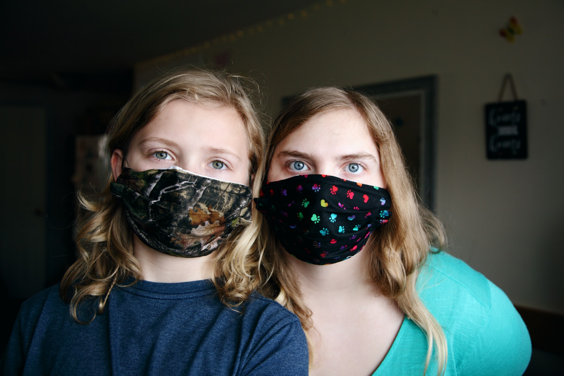 Eine Erwachsene und ein Kind, jeweils mit einer bunten Alltagsmaske mit schwarzem Grund. Beide schauen in die Kamera