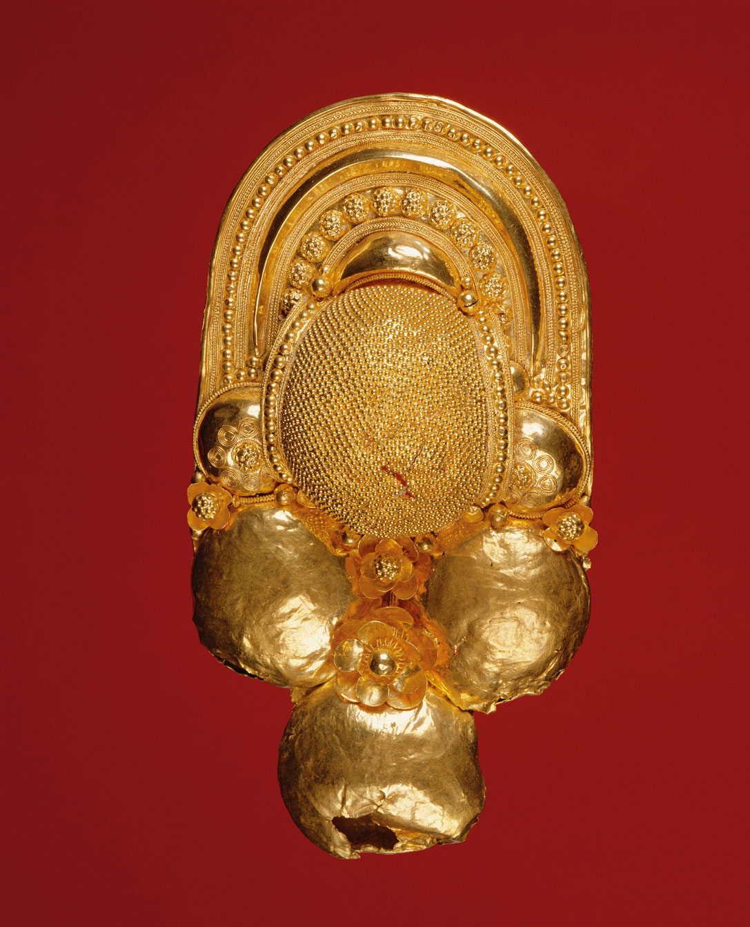 Goldbrosche, die unten aus drei Kugeln besteht und einen Aufsatz aus mehreren Ornamenten mit Blumen und einem Bogen hat.